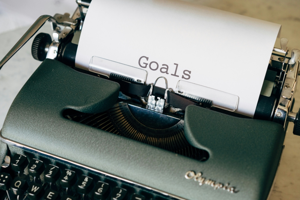 Maquina de escrever antiga papel inserido nela e com a palavra "Goals" escrito.
Gestão
